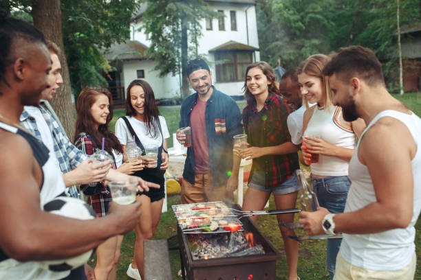 Grupo de amigos jóvenes disfrutando de una divertida barbacoa y fiesta al aire libre en el jardín